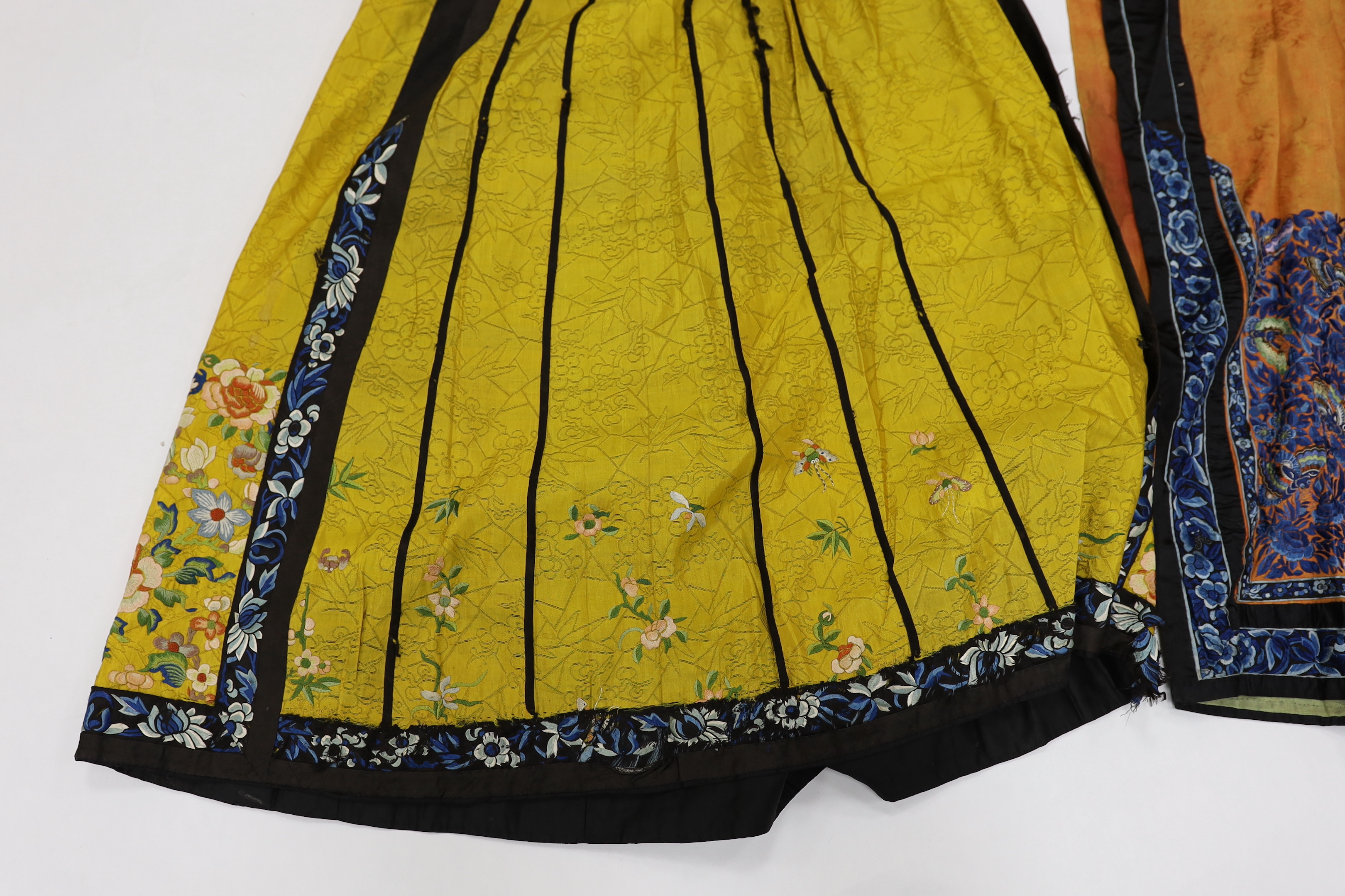 A late Chinese Qing yellow silk damask wedding skirt, with polychrome coloured silk embroidery, together with a similar coral silk damask blue embroidered wedding skirt